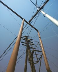 Low angle view of electricity pylon against clear blue sky