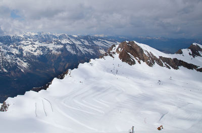 Scenic view of snow covered mountains against cloudy sky