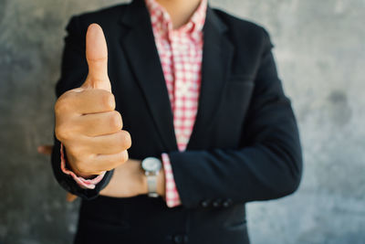 Midsection of businesswoman standing against wall