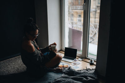 Woman using mobile phone while sitting at home