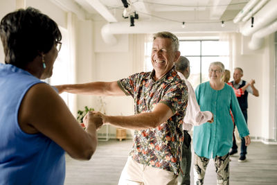 Happy multiracial senior couple dancing together in class