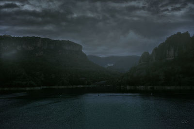 Scenic view of river by mountains against sky