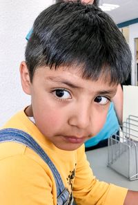 Side view of cute boy looking away while sitting indoors