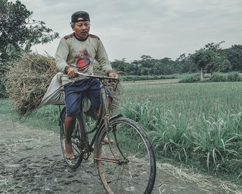 Man with bicycle on field against sky