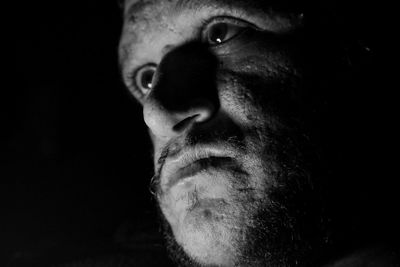 Close-up portrait of man against black background