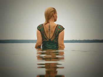 Rear view of woman standing at sea against sky