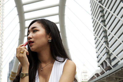 Woman applying lipstick in city