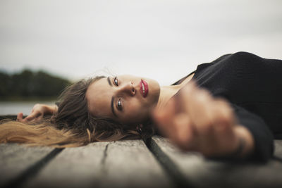 Portrait of woman lying on pier over lake