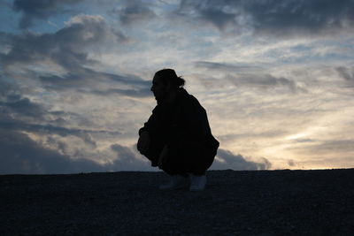 Silhouette man standing on road against sky during sunset