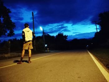 Rear view of man on road against sky at night