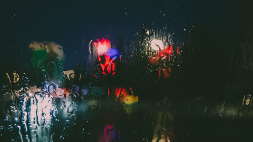 Illuminated lighting equipment seen through wet glass at night