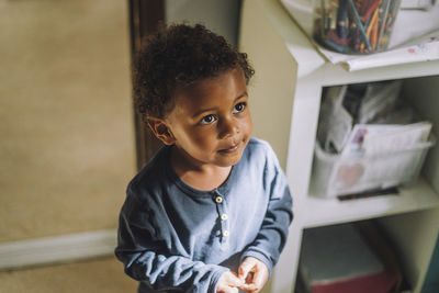 Innocent boy looking up while standing in day care center