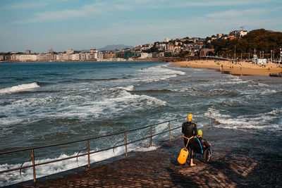 Rear view of people on sea against sky in city