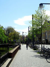 Footpath by street in city against sky