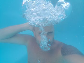 Shirtless man swimming underwater