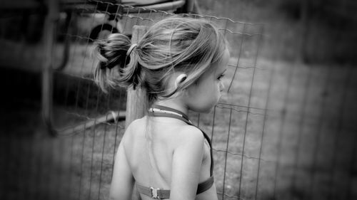 Side view of girl wearing swimwear looking through fence