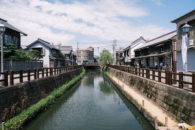 Bridge over river amidst buildings in city against sky