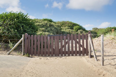 Wooden fence on beach against sky