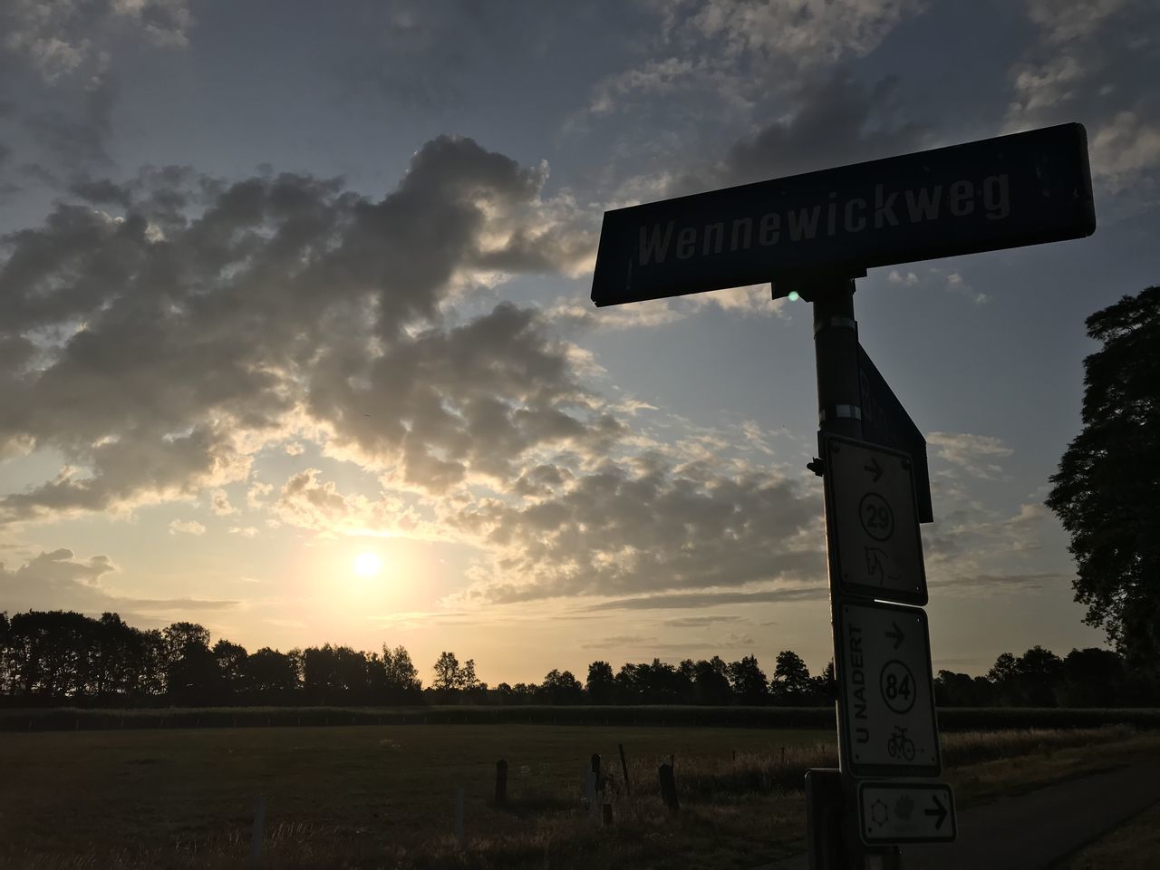 ROAD SIGN ON FIELD AGAINST SKY AT SUNSET