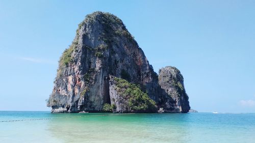 View of rock formation in sea against blue sky