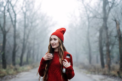 Alone young woman in red hat with thermos on nature background
