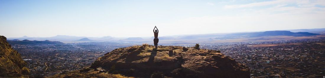 Rear view of man standing on mountain against sky