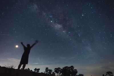 Low angle view of silhouette man standing against star field