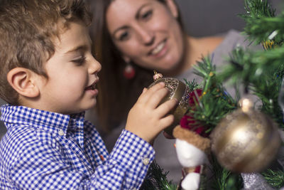 Mother and son decorating christmas tree at home