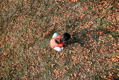 High angle view of girl crouching on field during autumn