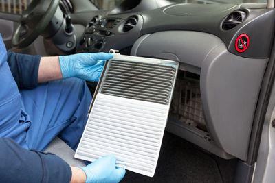 Midsection of man repairing air conditioner in car