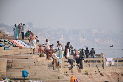 People standing by sea in city against sky