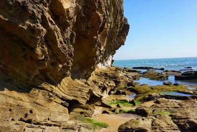 Rock formation on beach against clear sky