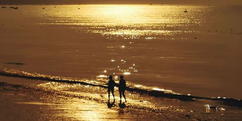 Silhouette man standing on beach against sky during sunset