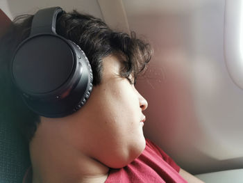 Boy relaxing listening to music on headphone during flight.