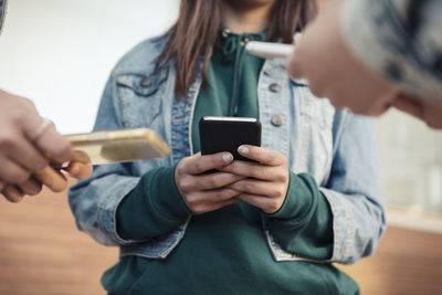 Cropped image of female friends using smart phone outdoors