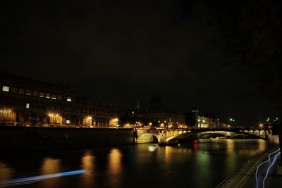 Illuminated bridge over river against sky at night