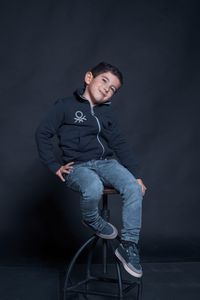 Portrait of young man standing against black background