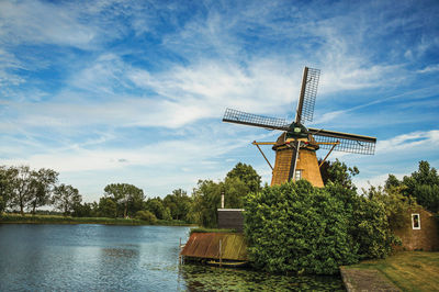 Traditional windmill on landscape against sky