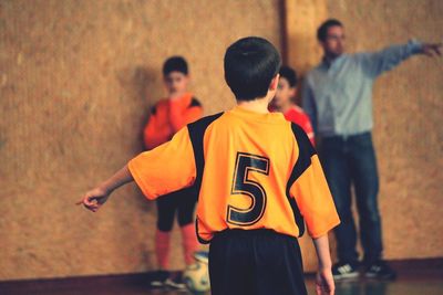 Rear view of boy pointing while playing soccer