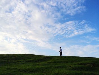 Man standing on field against cloudy sky