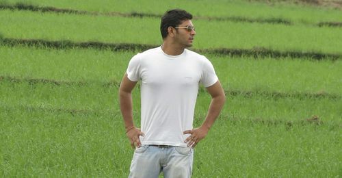 Young man with hands on hip while standing on grassy field