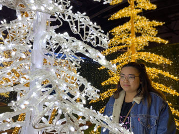 Young woman looking at illuminated christmas tree