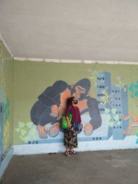 Full length of woman wearing mask standing against wall