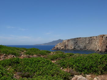 Scenic view of sea and mountains against blue sky