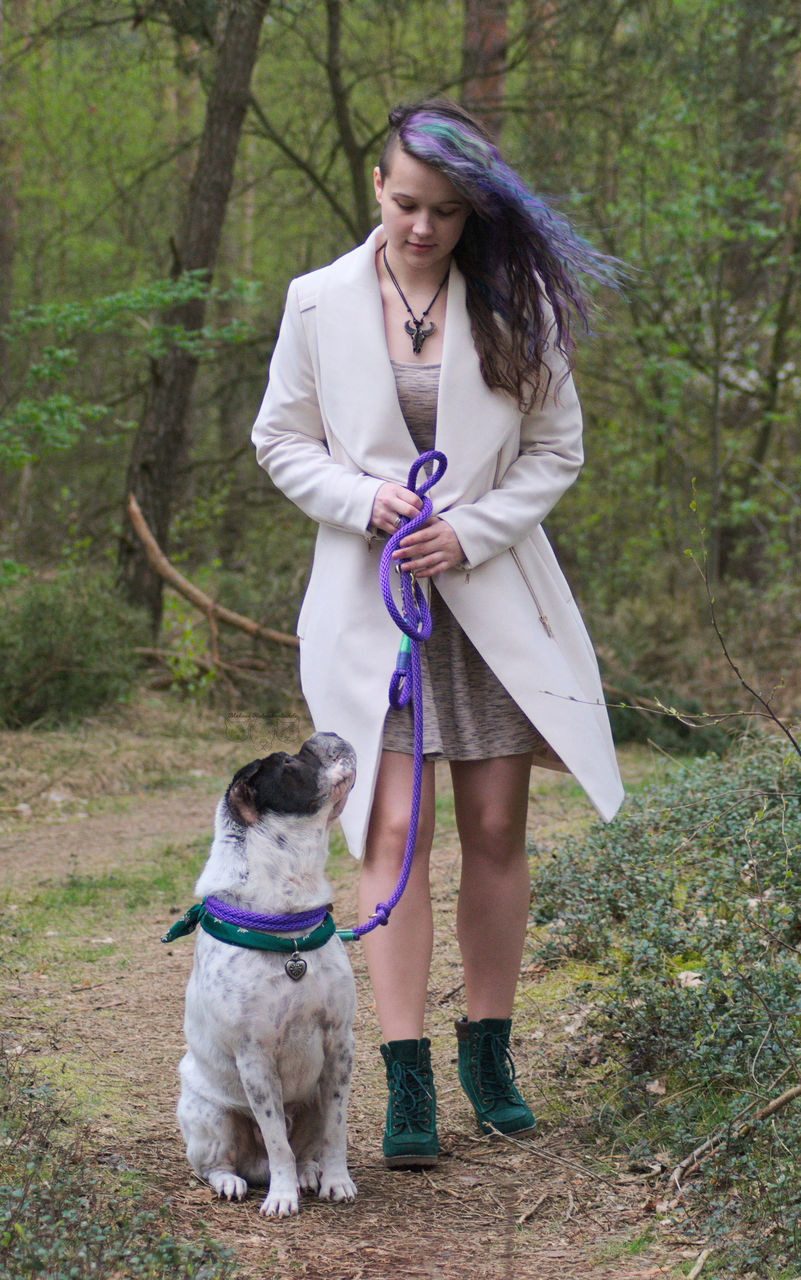 dog, pets, one animal, domestic animals, animal themes, one person, real people, full length, leisure activity, pet leash, young women, standing, mammal, day, front view, young adult, casual clothing, outdoors, lifestyles, holding, pet collar, tree, bonding, nature, friendship, adult, people