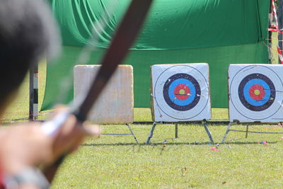 Rear view of man holding bow and arrow on field