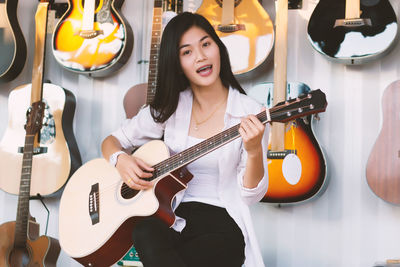 Portrait of young woman playing guitar in store