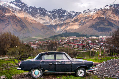 Car parked on field against mountains in town