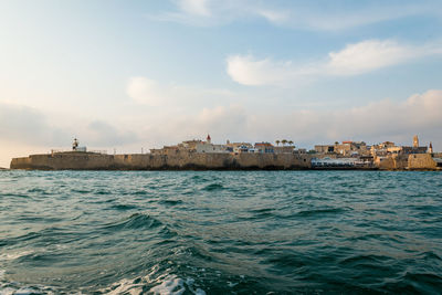 Sea by buildings against sky in city