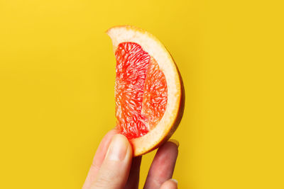 Female hand holding piece of a red grapefruit. healthy food concept. fresh orange juice. vegan